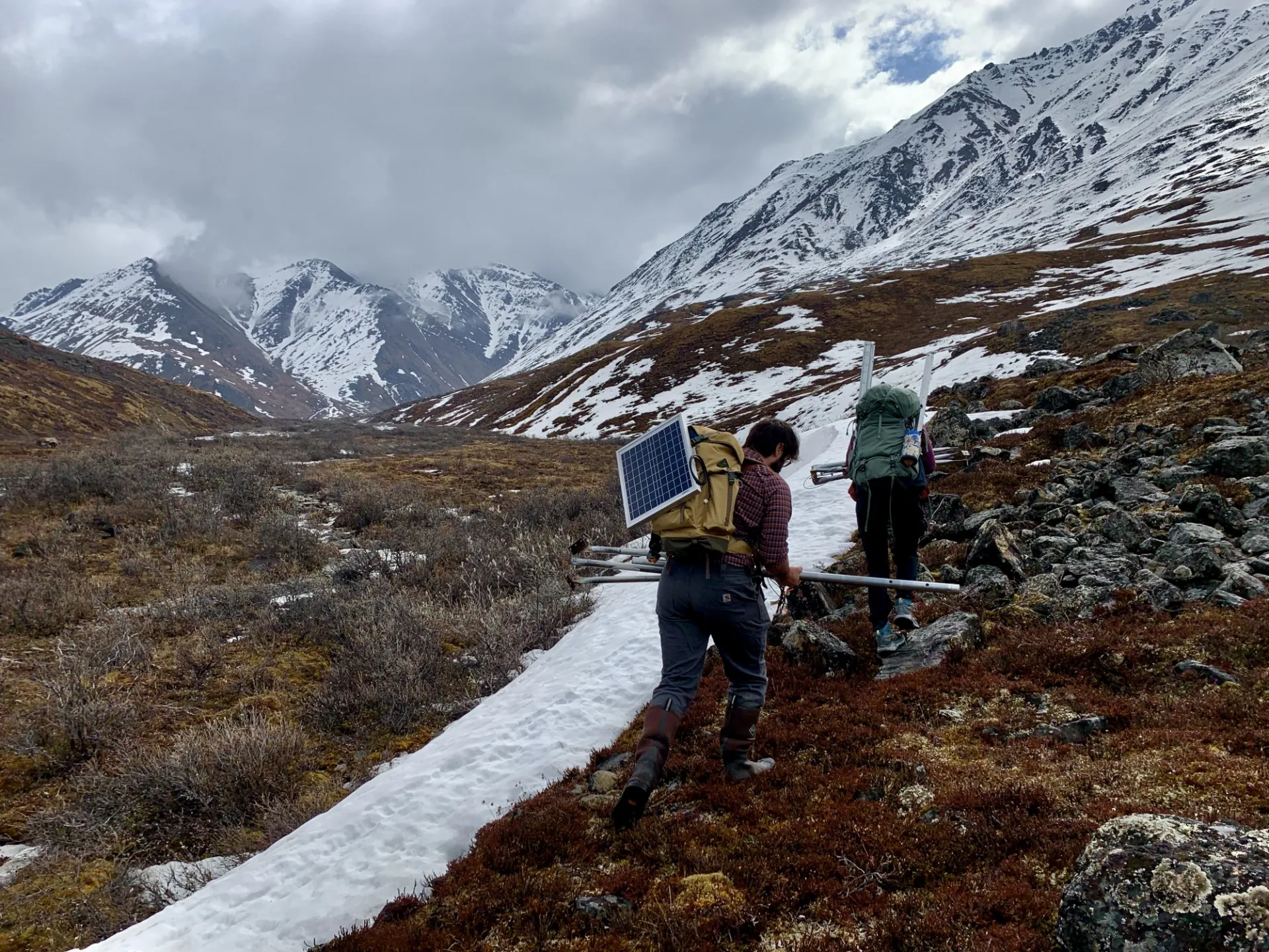 June is a month of chaos in the tundra, for both the landscape and the scientists. As snow from the long Arctic winter disappears, our team hauls solar panels, weather station equipment, and in situ stream chemistry sensors into the Brooks Range to keep up with the rapid seasonal changes. We hope to understand more about how Arctic stream nutrient concentrations change throughout space and time during the flow season, particularly as permafrost thaws and the active layer thickens. Credit: Abigail Rec