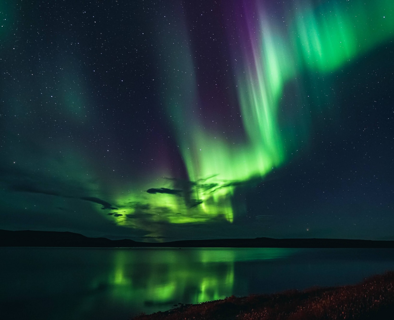 Jansen Nipko, undergraduate research student from Brigham Young University, captures the dazzling northern lights above Toolik Lake.